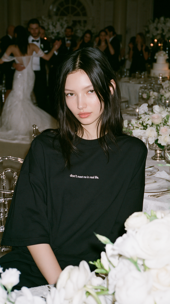WAAL LAB editorial campaign image of woman wearing black “don’t meet me in real life.” boxy tee at a wedding reception